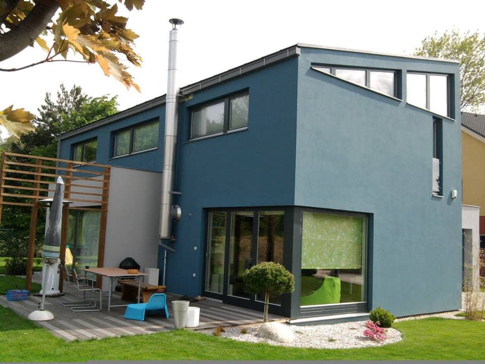 Modernes petrolfarbenes Haus mit Pergola und möblierter Terrasse